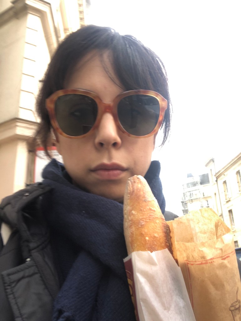 Shelby wearing sunglasses and holding baguettes